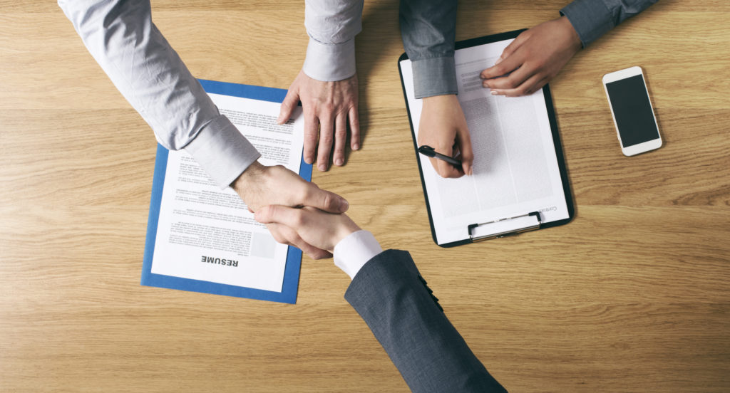 Employer hiring and giving an handshake to the candidate after the job interview hands close up top view