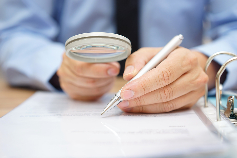 businessman is analyzing through magnifying glass contract and prices