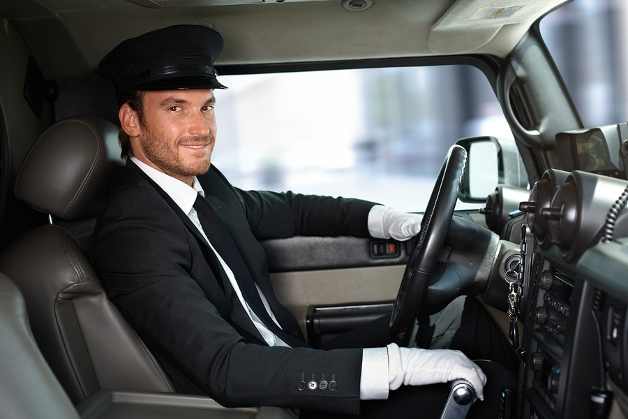 Handsome smiling chauffeur driving limousine.